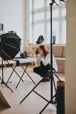 Kadın fotoğrafçı, arka plandaki objelerin fotoğrafını çekiyor. Profesyonel ekipmanlarla birlikte.