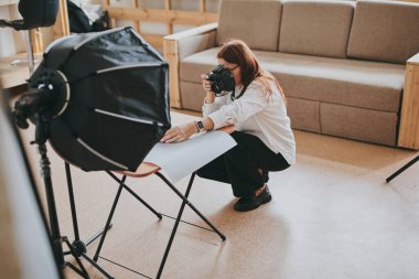 Kadın fotoğrafçı, arka plandaki objelerin fotoğrafını çekiyor. Profesyonel ekipmanlarla birlikte.