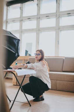 Kadın fotoğrafçı, arka plandaki objelerin fotoğrafını çekiyor. Profesyonel ekipmanlarla birlikte.