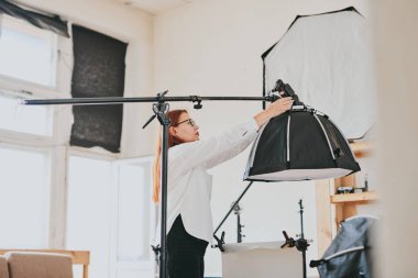 Kadın fotoğrafçı, arka plandaki objelerin fotoğrafını çekiyor. Profesyonel ekipmanlarla birlikte.