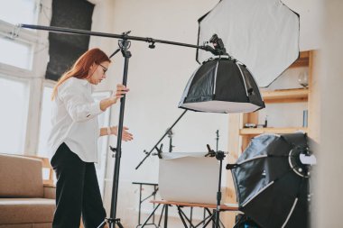 Kadın fotoğrafçı, arka plandaki objelerin fotoğrafını çekiyor. Profesyonel ekipmanlarla birlikte.