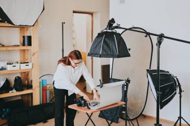 Kadın fotoğrafçı, arka plandaki objelerin fotoğrafını çekiyor. Profesyonel ekipmanlarla birlikte.