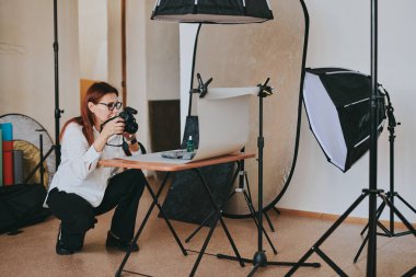 Kadın fotoğrafçı, arka plandaki objelerin fotoğrafını çekiyor. Profesyonel ekipmanlarla birlikte.