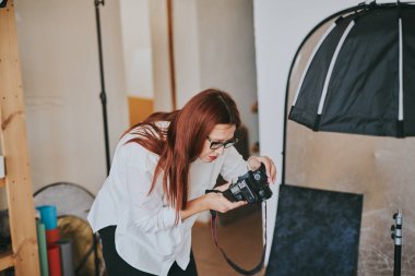 Kadın fotoğrafçı, arka plandaki objelerin fotoğrafını çekiyor. Profesyonel ekipmanlarla birlikte.