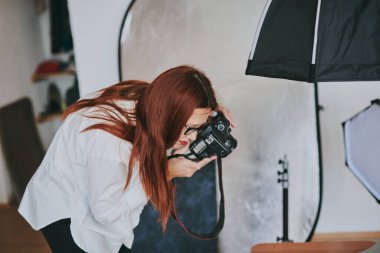 Kadın fotoğrafçı, arka plandaki objelerin fotoğrafını çekiyor. Profesyonel ekipmanlarla birlikte.
