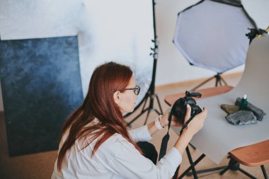 Kadın fotoğrafçı, arka plandaki objelerin fotoğrafını çekiyor. Profesyonel ekipmanlarla birlikte.