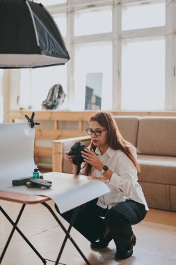 Kadın fotoğrafçı, arka plandaki objelerin fotoğrafını çekiyor. Profesyonel ekipmanlarla birlikte.