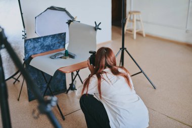 Kadın fotoğrafçı, arka plandaki objelerin fotoğrafını çekiyor. Profesyonel ekipmanlarla birlikte.