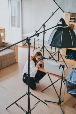 Kadın fotoğrafçı, arka plandaki objelerin fotoğrafını çekiyor. Profesyonel ekipmanlarla birlikte.