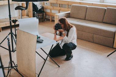 Kadın fotoğrafçı, arka plandaki objelerin fotoğrafını çekiyor. Profesyonel ekipmanlarla birlikte.