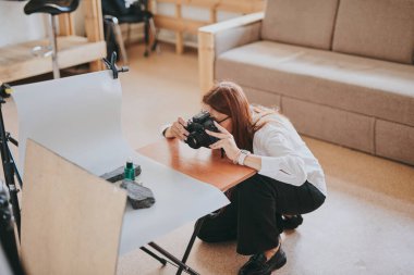 Kadın fotoğrafçı, arka plandaki objelerin fotoğrafını çekiyor. Profesyonel ekipmanlarla birlikte.