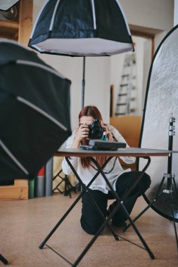 Kadın fotoğrafçı, arka plandaki objelerin fotoğrafını çekiyor. Profesyonel ekipmanlarla birlikte.