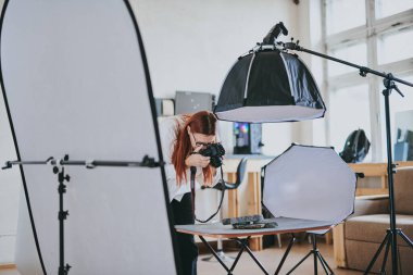 Kadın fotoğrafçı, arka plandaki objelerin fotoğrafını çekiyor. Profesyonel ekipmanlarla birlikte.