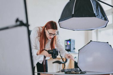 Kadın fotoğrafçı, arka plandaki objelerin fotoğrafını çekiyor. Profesyonel ekipmanlarla birlikte.