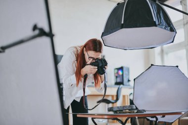 Kadın fotoğrafçı, arka plandaki objelerin fotoğrafını çekiyor. Profesyonel ekipmanlarla birlikte.