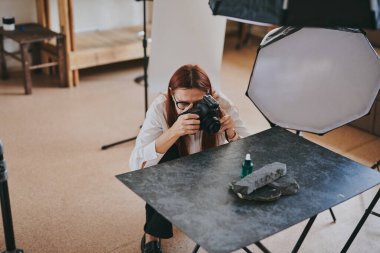 Kadın fotoğrafçı, arka plandaki objelerin fotoğrafını çekiyor. Profesyonel ekipmanlarla birlikte.