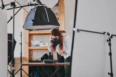 Kadın fotoğrafçı, arka plandaki objelerin fotoğrafını çekiyor. Profesyonel ekipmanlarla birlikte.