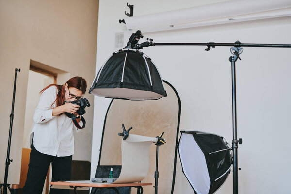 Женщина-фотограф фотографирует на заднем плане в фотостудии с профессиональным оборудованием