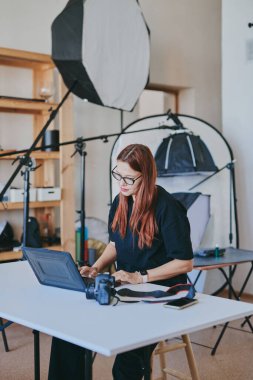 Profesyonel fotoğraf stüdyosunda dizüstü bilgisayarlı kadın fotoğrafçı.