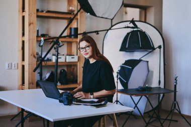Profesyonel fotoğraf stüdyosunda dizüstü bilgisayarlı kadın fotoğrafçı.
