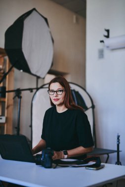 Profesyonel fotoğraf stüdyosunda dizüstü bilgisayarlı kadın fotoğrafçı.