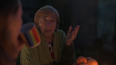 Yaşlı beyaz bir büyükanne ve yetişkin kızı bayram bayramını şenlik masasında kutluyor.