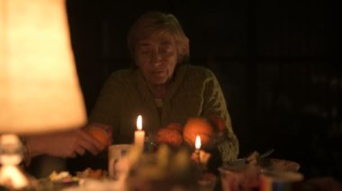 Yaşlı beyaz bir büyükanne ve yetişkin kızı bayram bayramını şenlik masasında kutluyor.