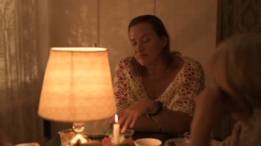 Yaşlı beyaz bir büyükanne ve yetişkin kızı bayram bayramını şenlik masasında kutluyor.