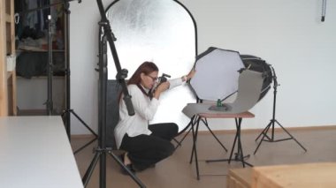 Kadın fotoğrafçı, arka plandaki objelerin fotoğrafını çekiyor. Profesyonel ekipmanlarla birlikte.