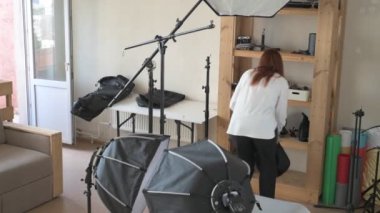 Kadın fotoğrafçı, profesyonel fotoğraf stüdyosunda fotoğraf çekimi için ekipman hazırlıyor.