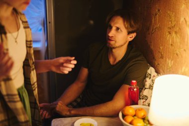 Sevgililer Günü 'nü bastırılmış sıcak aydınlatma altında, rahat evlerinde kutlayan mutlu genç çift.