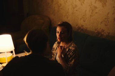 Sevgililer Günü 'nü bastırılmış sıcak aydınlatma altında, rahat evlerinde kutlayan mutlu genç çift.