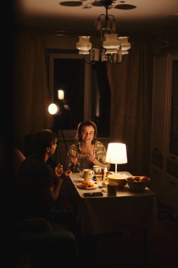 Sevgililer Günü 'nü bastırılmış sıcak aydınlatma altında, rahat evlerinde kutlayan mutlu genç çift.