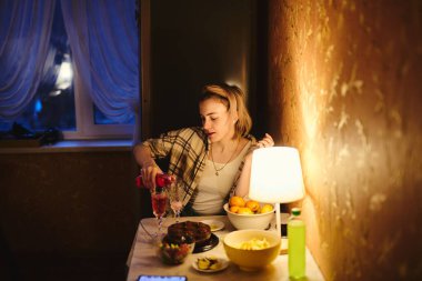 Genç sarışın bir kadının portresi. Gülümsüyor ve mutfakta şenlikli bir yemek yiyor.