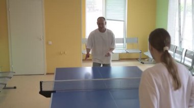 Masa tenisi oynayan iki kişi. Kadın ve erkek masa tenisi kulübünde yarışıyor.