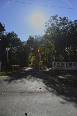 Küçük bir kasabanın sonbahar manzarası. Turuncu yapraklarla kaplı köy evleri ve yollar