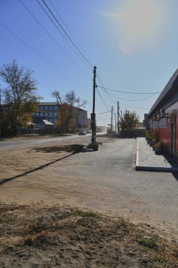 Küçük bir kasabanın sonbahar manzarası. Turuncu yapraklarla kaplı köy evleri ve yollar