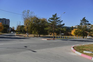 Küçük bir kasabanın sonbahar manzarası. Turuncu yapraklarla kaplı köy evleri ve yollar