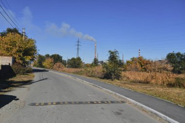 Küçük bir kasabanın sonbahar manzarası. Turuncu yapraklarla kaplı köy evleri ve yollar