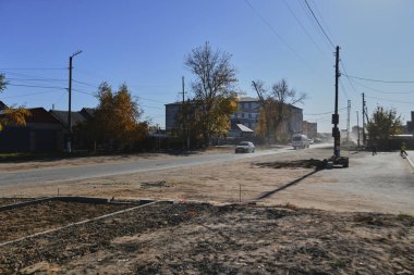 Küçük bir kasabanın sonbahar manzarası. Turuncu yapraklarla kaplı köy evleri ve yollar