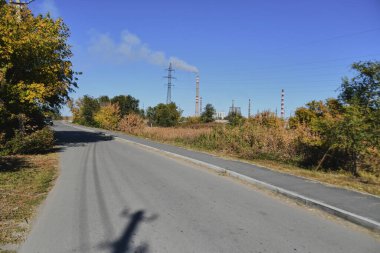 Küçük bir kasabanın sonbahar manzarası. Turuncu yapraklarla kaplı köy evleri ve yollar