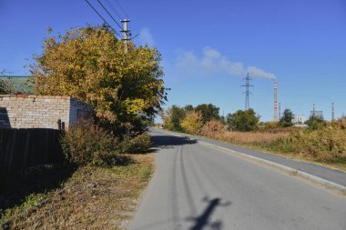 Küçük bir kasabanın sonbahar manzarası. Turuncu yapraklarla kaplı köy evleri ve yollar