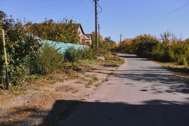 Küçük bir kasabanın sonbahar manzarası. Turuncu yapraklarla kaplı köy evleri ve yollar