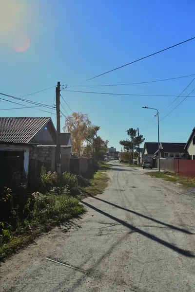 Küçük bir kasabanın sonbahar manzarası. Turuncu yapraklarla kaplı köy evleri ve yollar