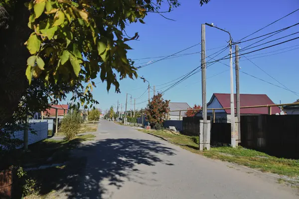 Küçük bir kasabanın sonbahar manzarası. Turuncu yapraklarla kaplı köy evleri ve yollar