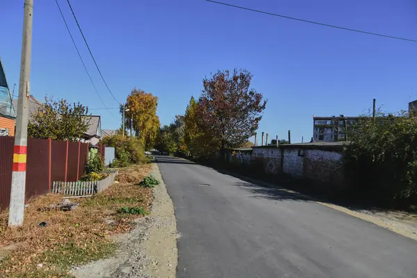 Küçük bir kasabanın sonbahar manzarası. Turuncu yapraklarla kaplı köy evleri ve yollar