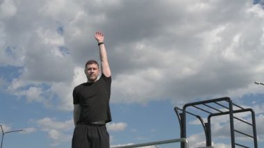 Bir erkek sporcu dışarıda spor alanında antrenman yapıyor. Beyaz erkek sporcu yaz parkında antrenman yapmadan önce ısınma egzersizi yapıyor.