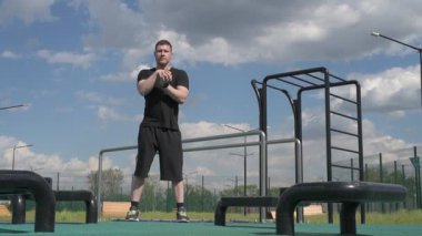 Bir erkek sporcu dışarıda spor alanında antrenman yapıyor. Beyaz erkek sporcu yaz parkında antrenman yapmadan önce ısınma egzersizi yapıyor.