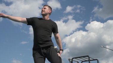 Bir erkek sporcu dışarıda spor alanında antrenman yapıyor. Beyaz erkek sporcu yaz parkında antrenman yapmadan önce ısınma egzersizi yapıyor.