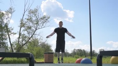 Bir erkek sporcu dışarıda spor alanında antrenman yapıyor. Beyaz erkek sporcu yaz parkında antrenman yapmadan önce ısınma egzersizi yapıyor.